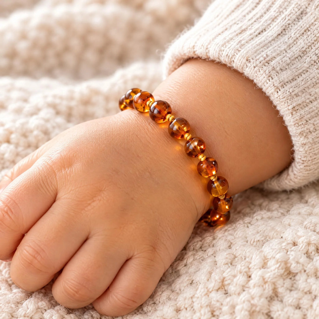 Bracelet ambre bébé baroque cognac porté par un bébé | Terre d'Ambre